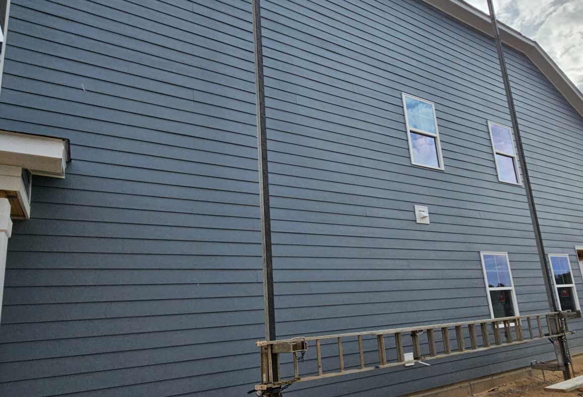 A large blue house with a ladder leaning against it.