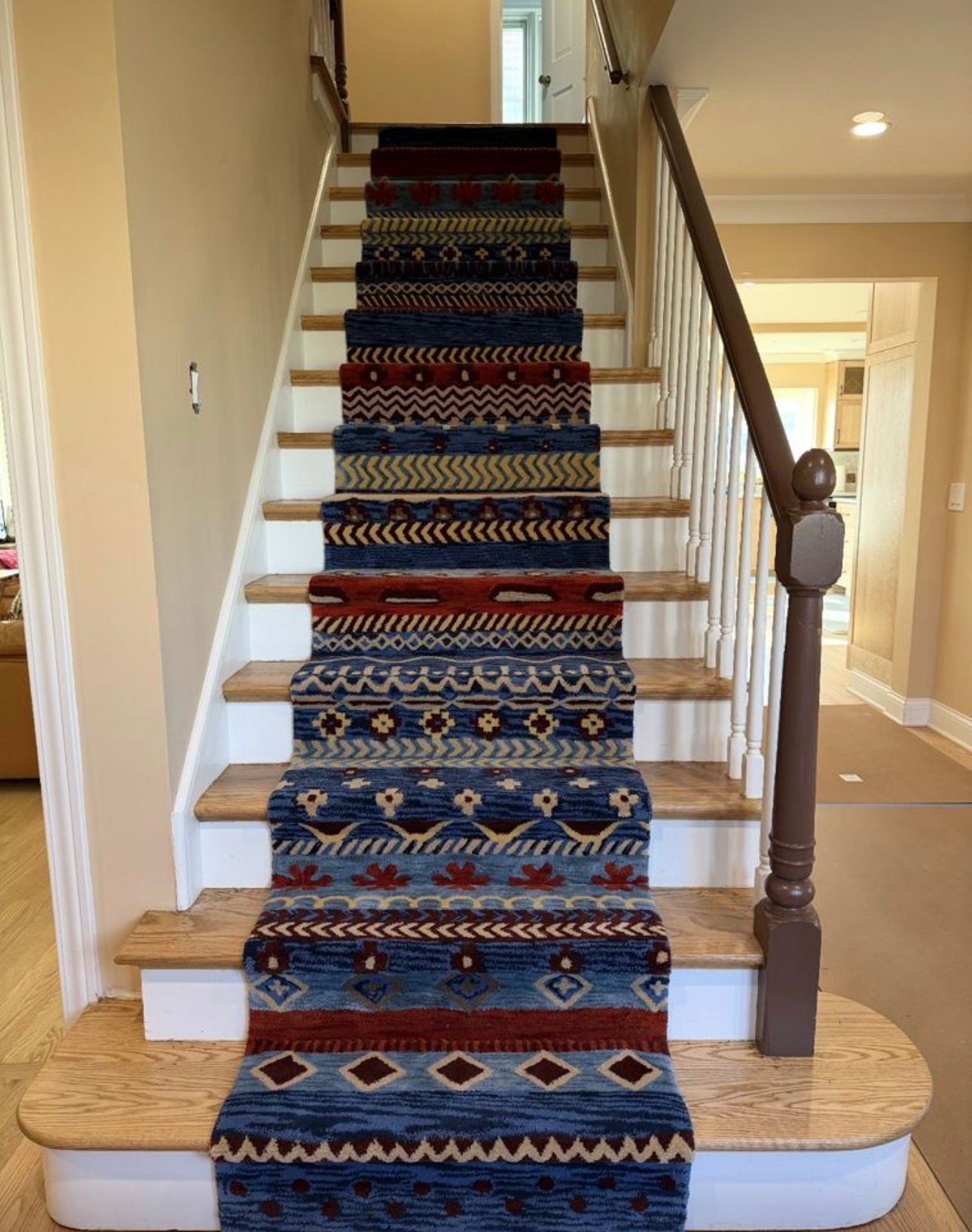 Carpet runner on a white staircase with wooden banister in a beige hallway