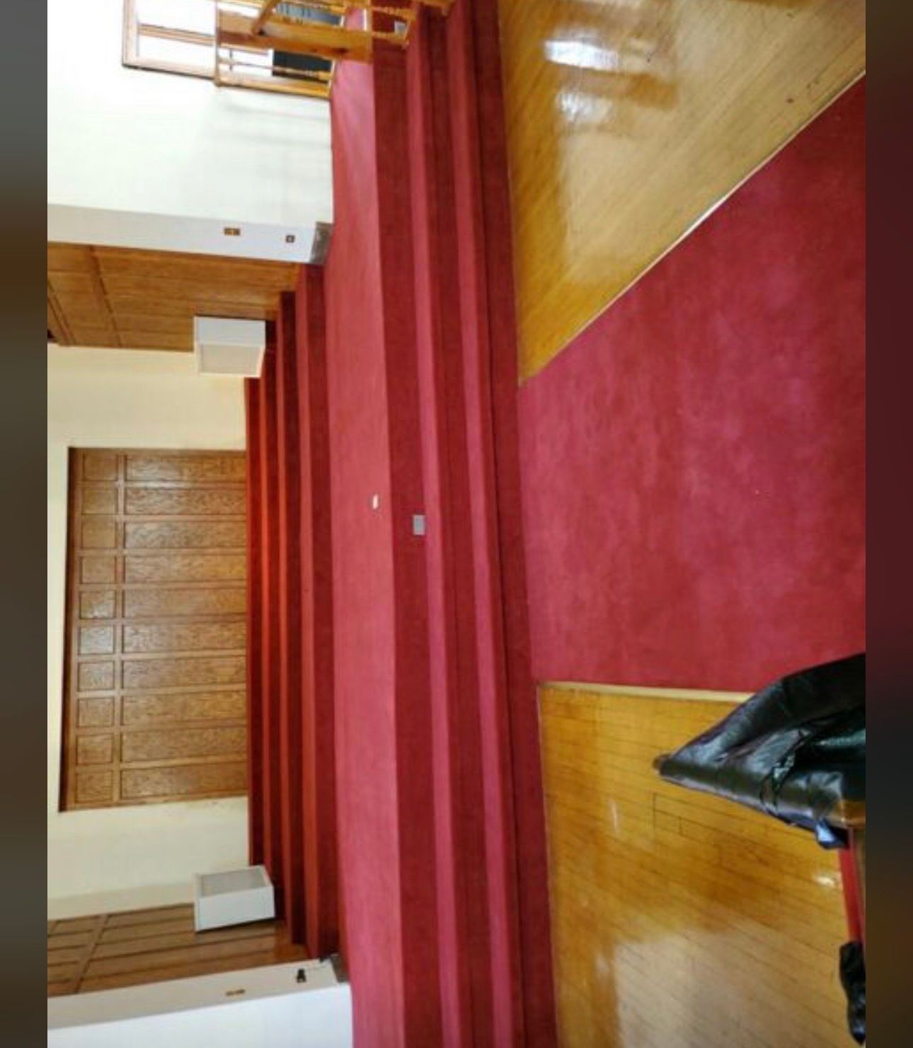 Interior room with red carpet and wood floors, featuring a staircase and a red curtain divider.
