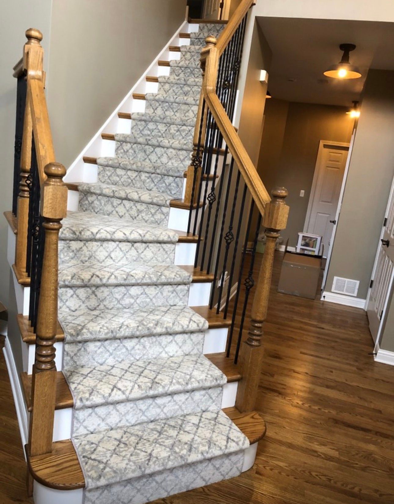 Carpeted staircase with wooden banisters in a home interior, leading to an upstairs hallway.