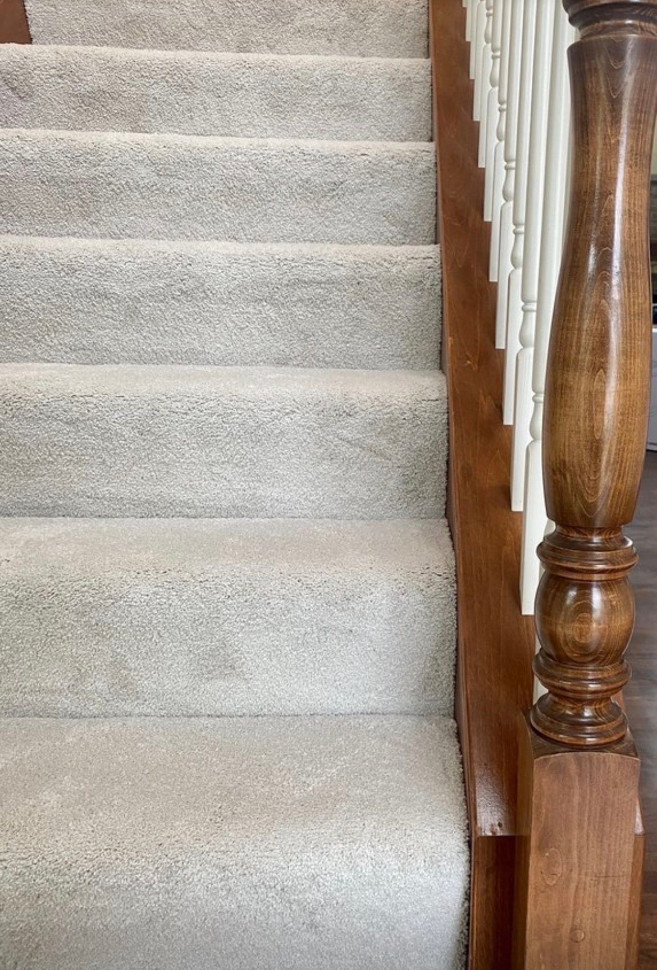Carpeted staircase beside a wooden banister and newel post
