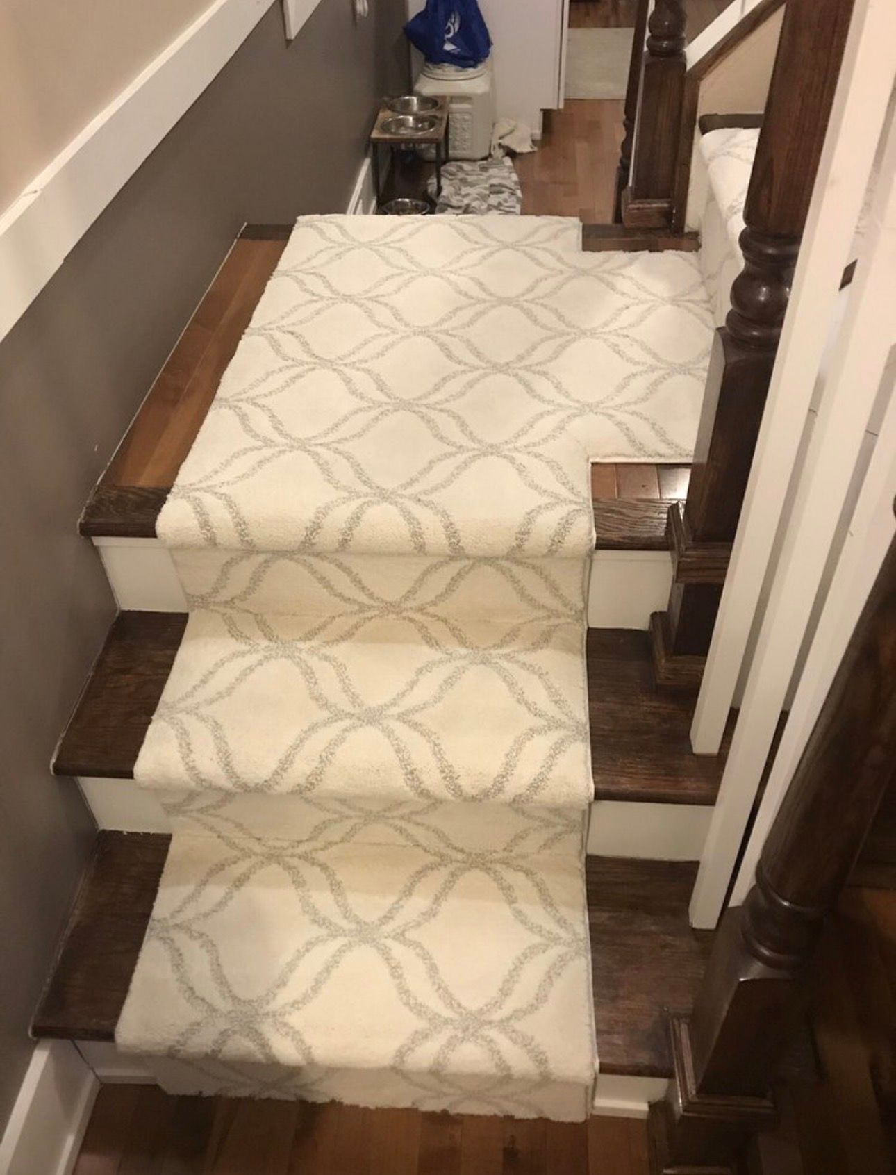 Carpeted stairs with beige runner and dark wood rails in a narrow hallway