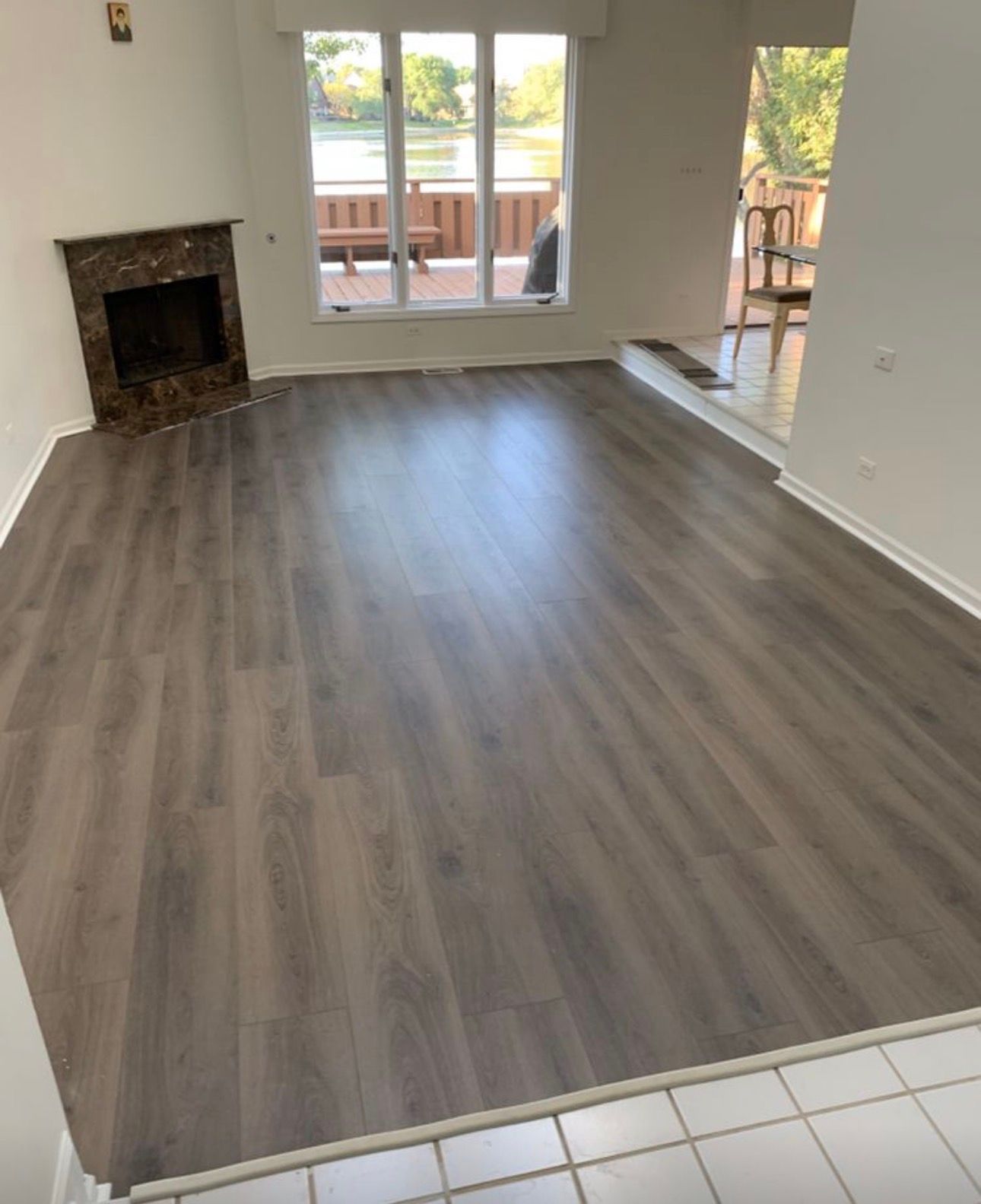Empty living room with gray wood floors, fireplace, and sliding glass doors to a deck