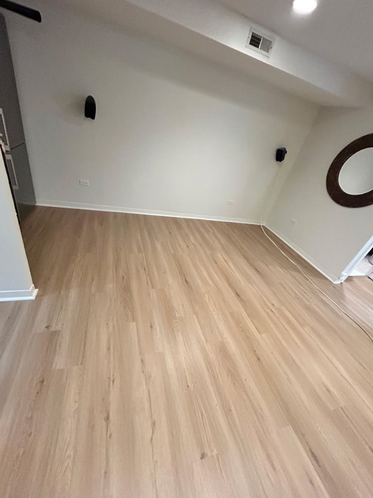 Empty room with light wood flooring, white walls, and black wall lights, viewed from a doorway.
