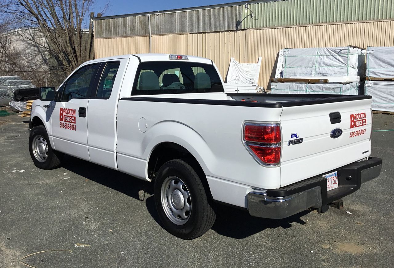 White pickup truck parked outside, with company logo and lumber in the background.