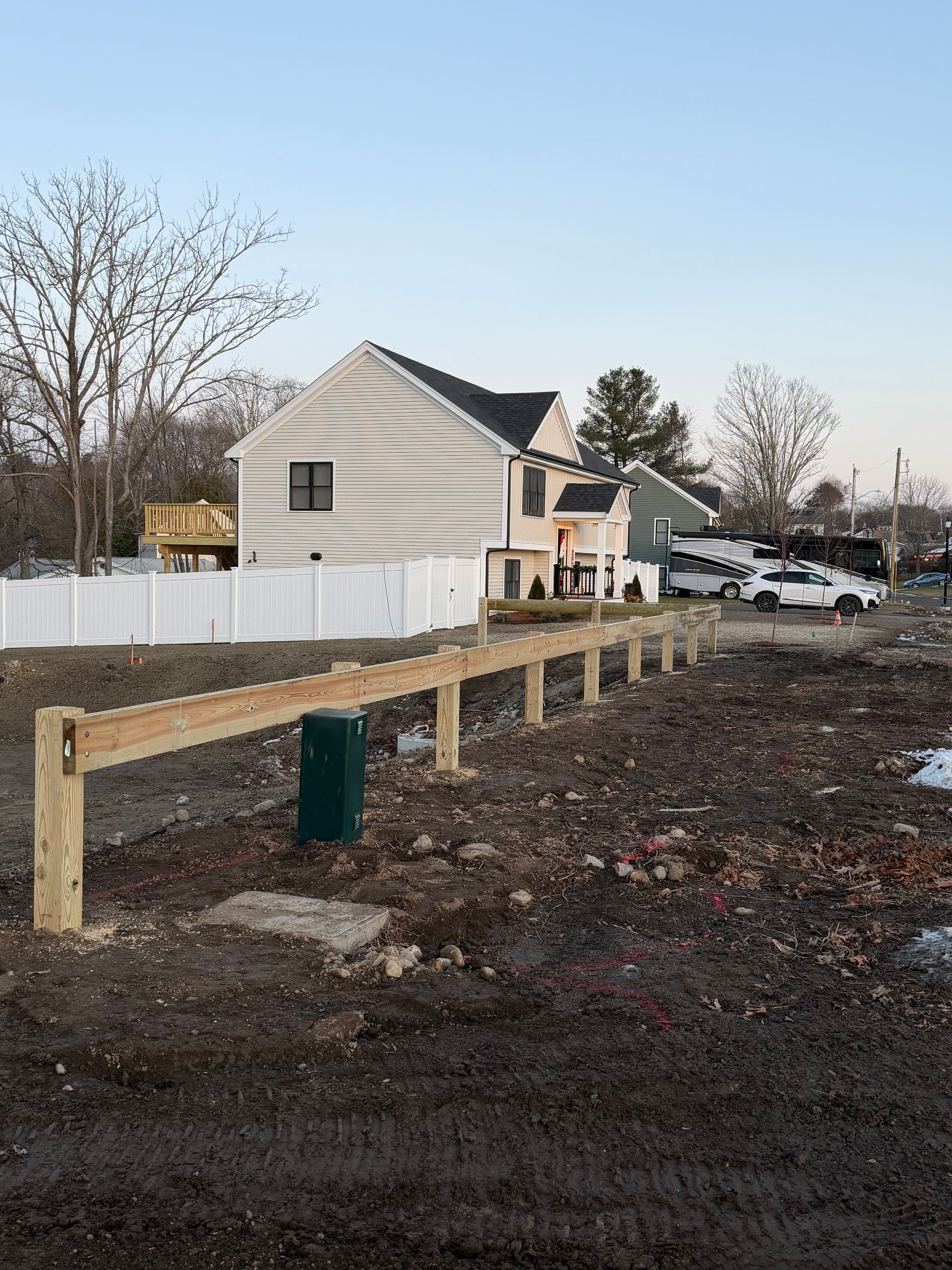 Wooden fence under construction in front of a house. Bare ground.