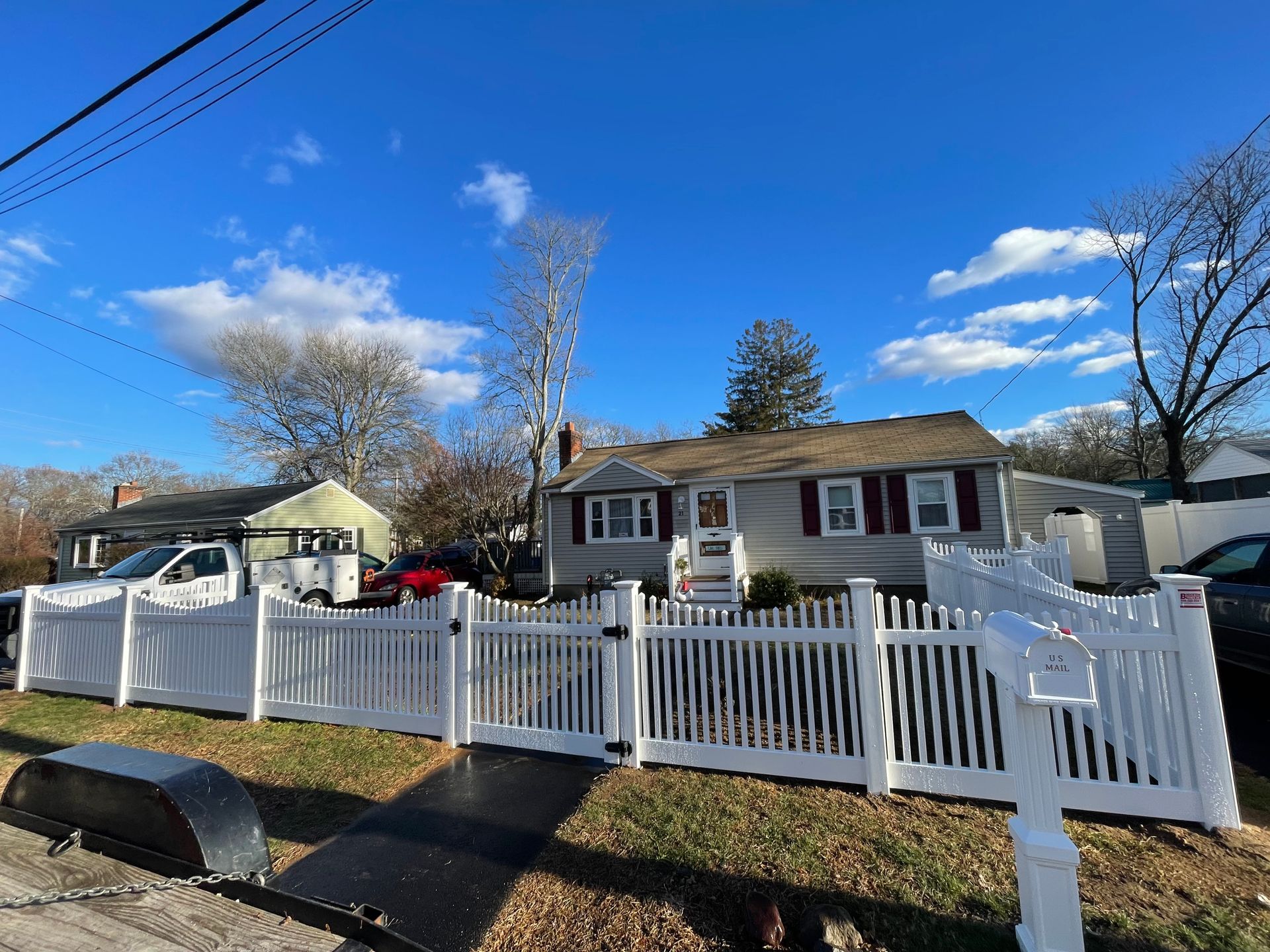 A gray house with white picket fence under a partly cloudy sky.