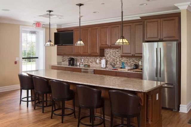 Kitchen with island seating, wood cabinets, stainless steel appliances, and pendant lights