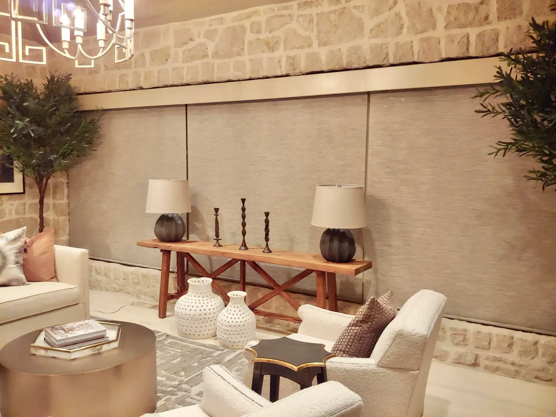 Living room with stone wall, wooden bench, lamps, and decorative vases.
