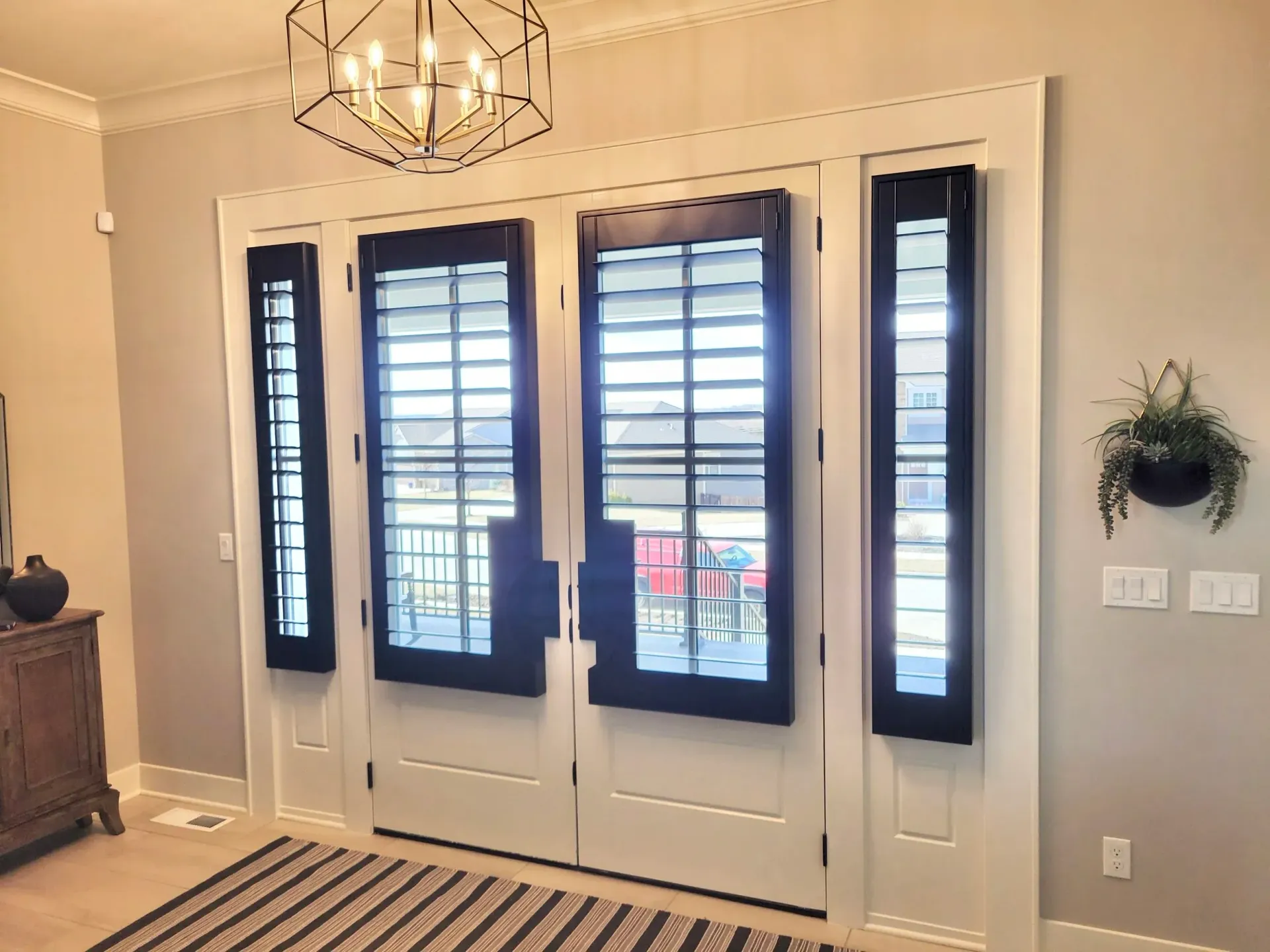 Entryway with white door frame, black shutters, and striped rug.