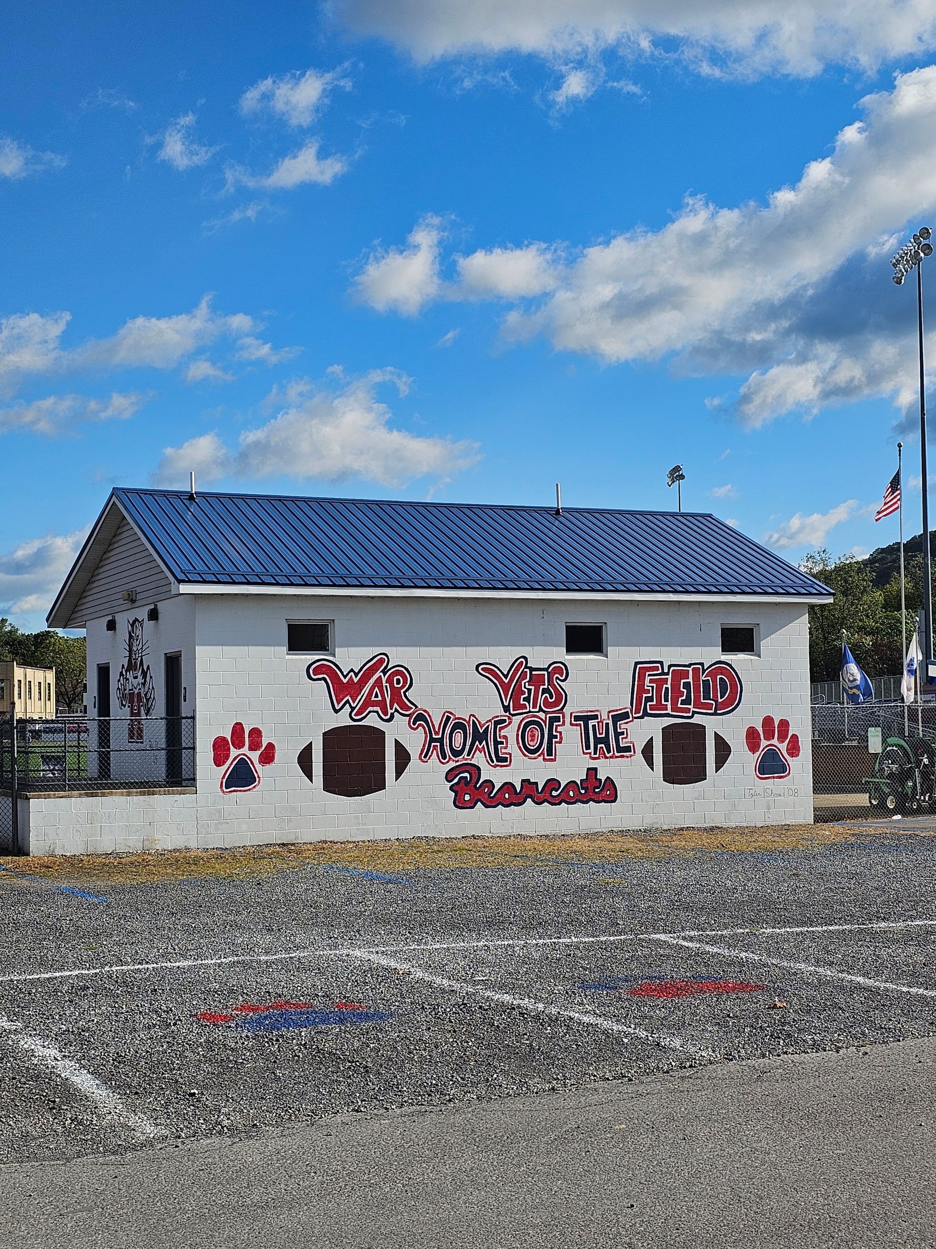 A white building with a blue roof is sitting in a gravel lot.