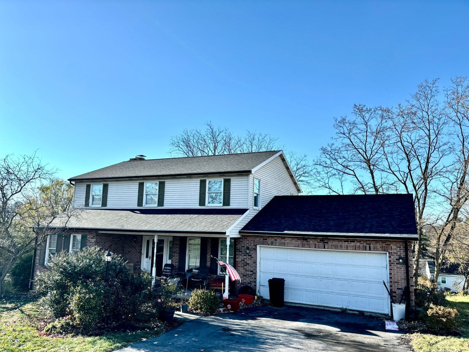 A large white house with a black roof and a large garage.