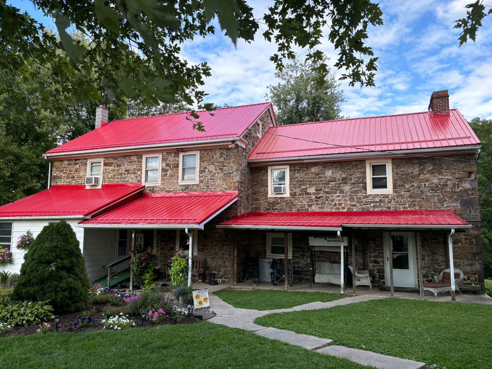 A large stone house with a red roof and a porch.
