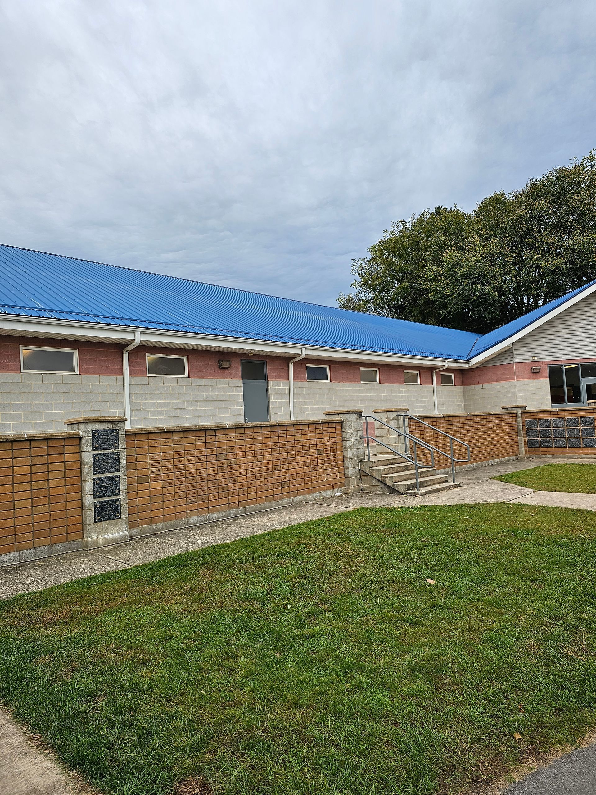 A house with a blue roof and a brick fence in front of it.