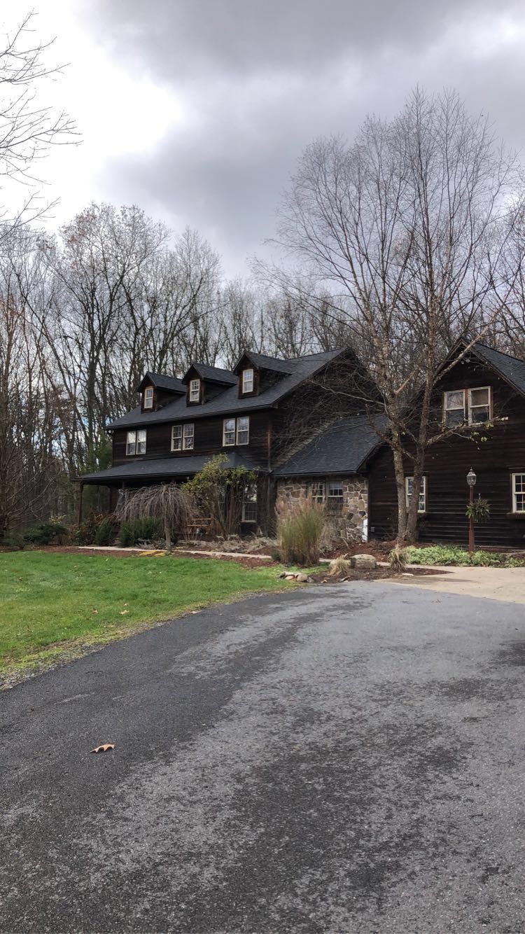 A large house with a lot of windows is surrounded by trees and grass.