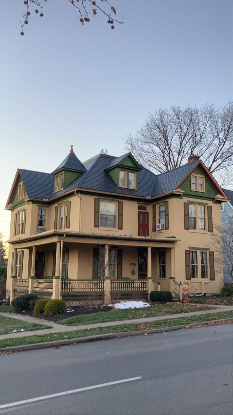 A large yellow house with a blue roof and a porch.
