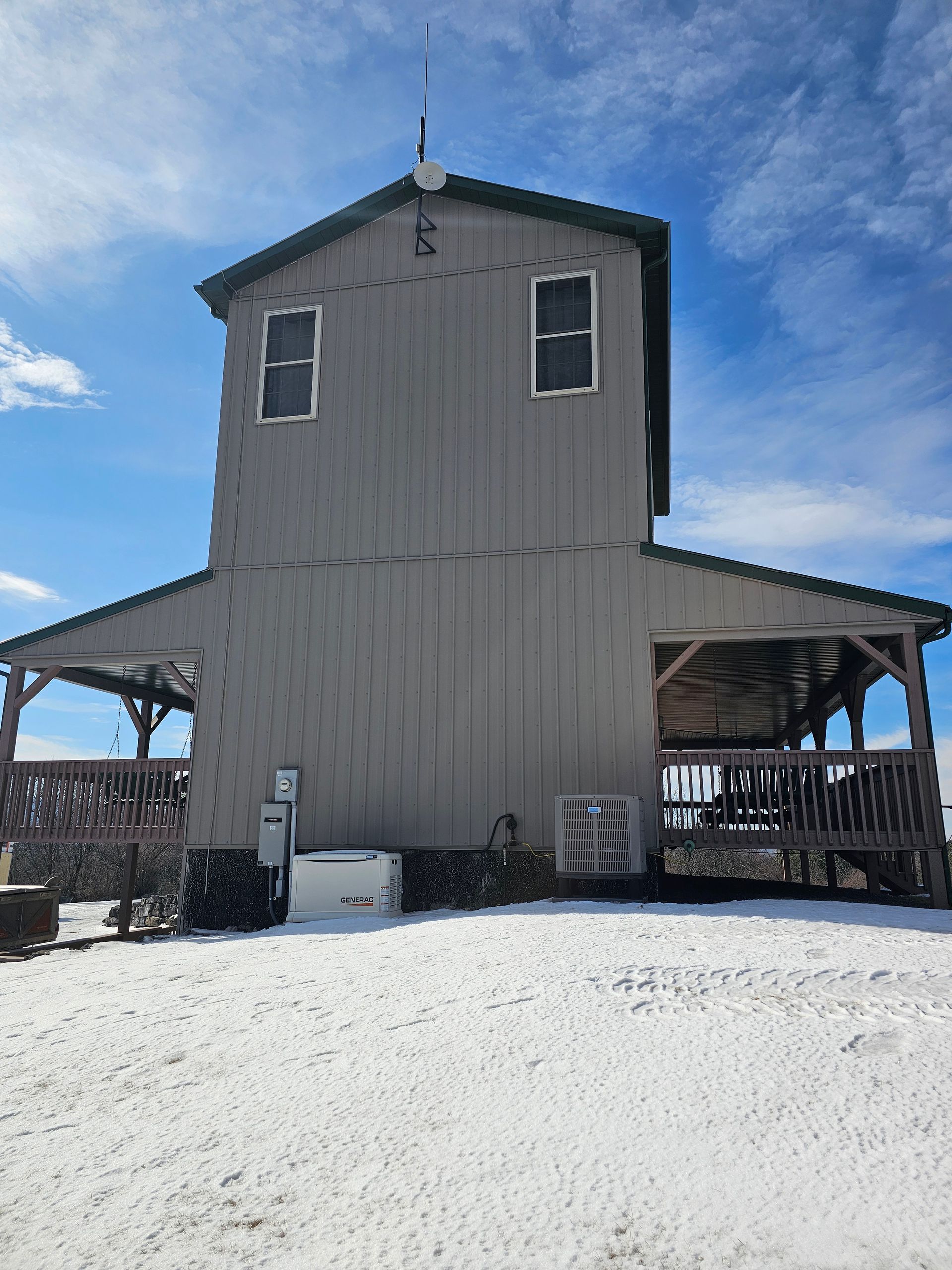 A large gray building with a green roof is sitting in the snow.
