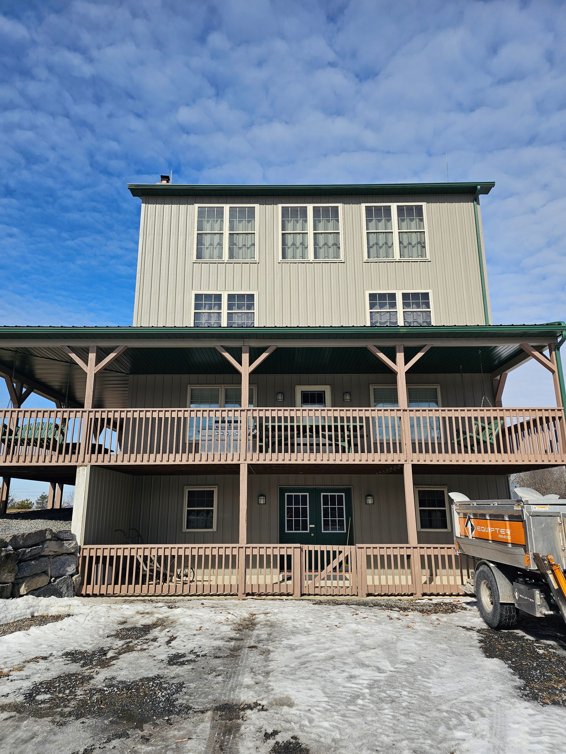 A large house with a large deck and a truck parked in front of it.