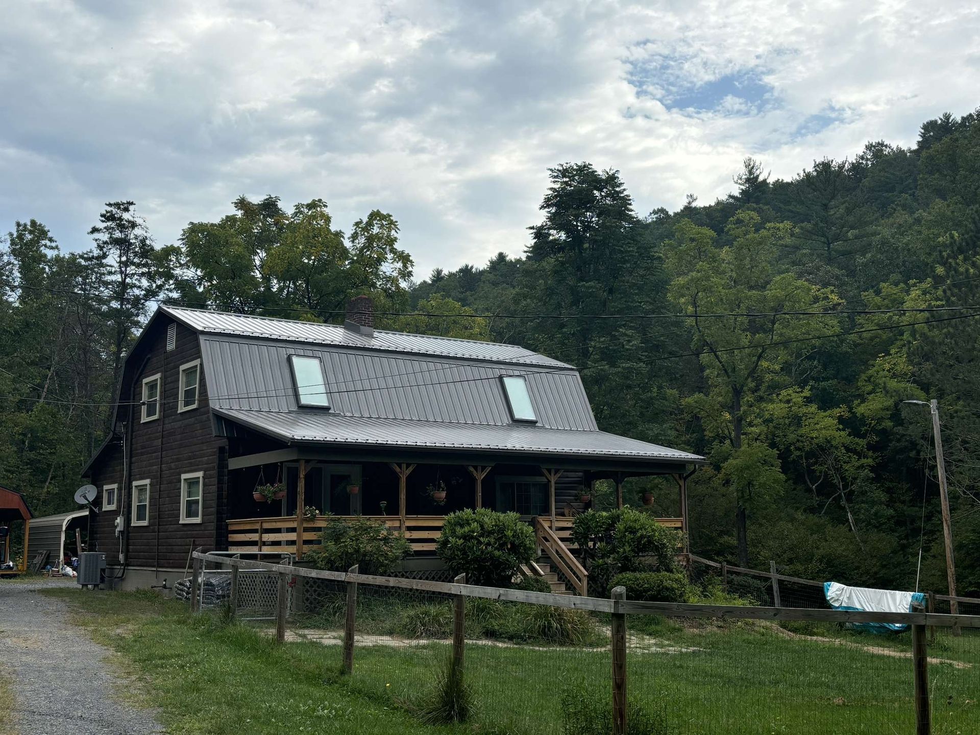 A large house with a porch is surrounded by trees and grass.
