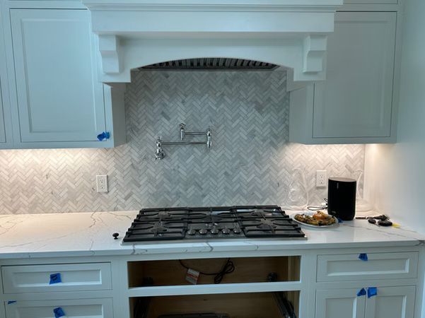 White kitchen with gas cooktop, marble backsplash, and partially installed cabinets and drawers