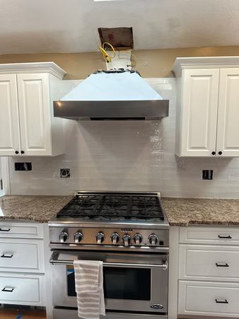 Kitchen with stainless steel range and hood, white cabinets, granite counters, and exposed wiring above the hood