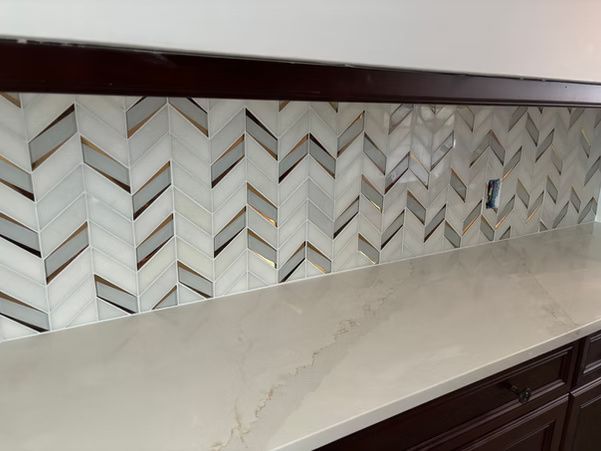 Modern kitchen countertop with white herringbone tile backsplash and dark wood cabinets