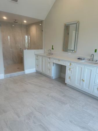 Spacious bathroom with double vanity, large mirror, walk-in shower, and light tile flooring