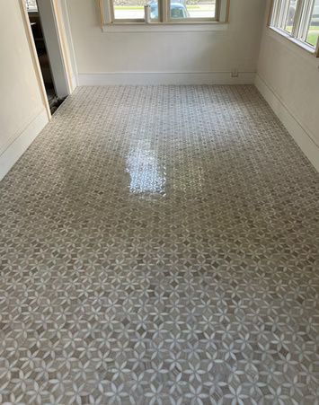 Empty room with patterned gray carpet and bright windows on both sides.