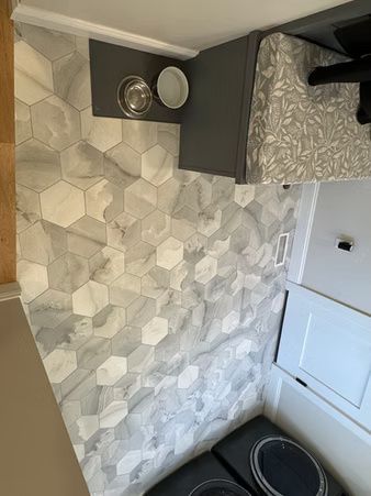 Small bathroom corner with hex tile wall, dark vanity, sink, and gray patterned shower curtain.
