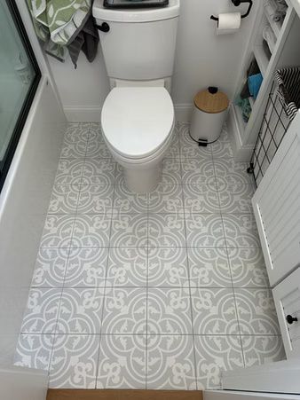 Small bathroom with a white toilet and light gray patterned tile floor, viewed from the doorway.