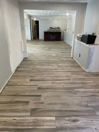 Empty renovated room with light wood flooring, white walls, and a dark console at the far end