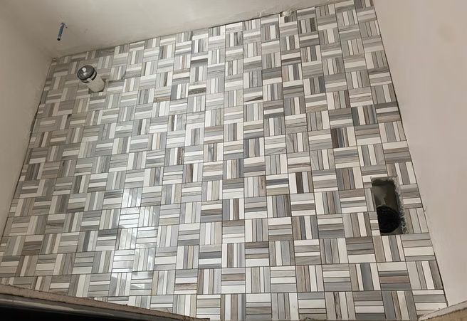 Metal patterned panel with a small hole and fastener on a light-colored wall.