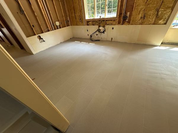 Empty room under construction with exposed wooden walls and a beige subfloor near a window.