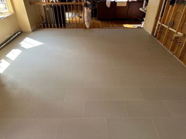 Empty room with light gray tile floor and sunlight from windows on the left.