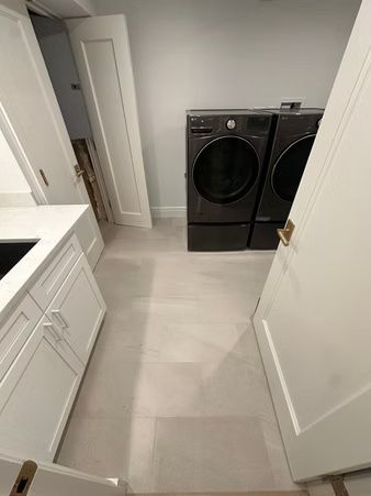 Laundry room with front-loading washer and dryer in a narrow, light gray hallway