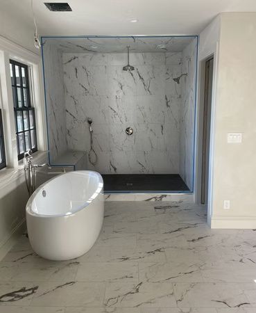 Modern bathroom with marble tile, freestanding tub, and walk-in shower in a sleek gray interior