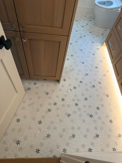 Bathroom floor with star-patterned linoleum, wooden cabinets, and a toilet in the background.