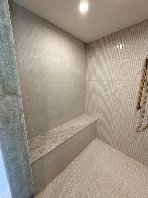 Modern tiled steam shower with built-in bench and handheld showerhead.