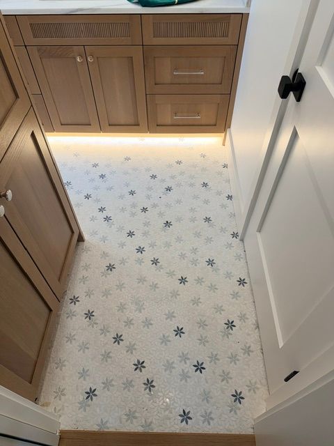 Kitchen floor with white star-patterned vinyl and warm under-cabinet lighting between cabinets and a door.