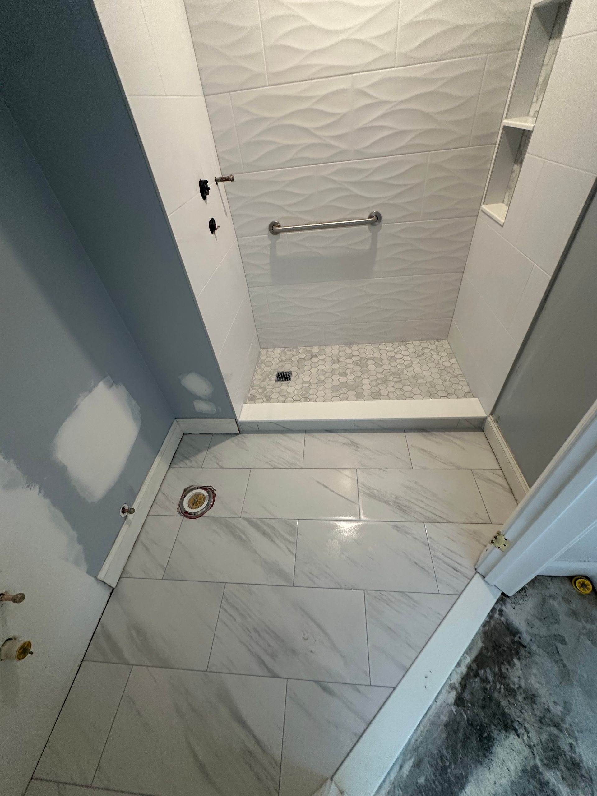 Small bathroom with white tile floor, shower stall, and gray-blue walls.