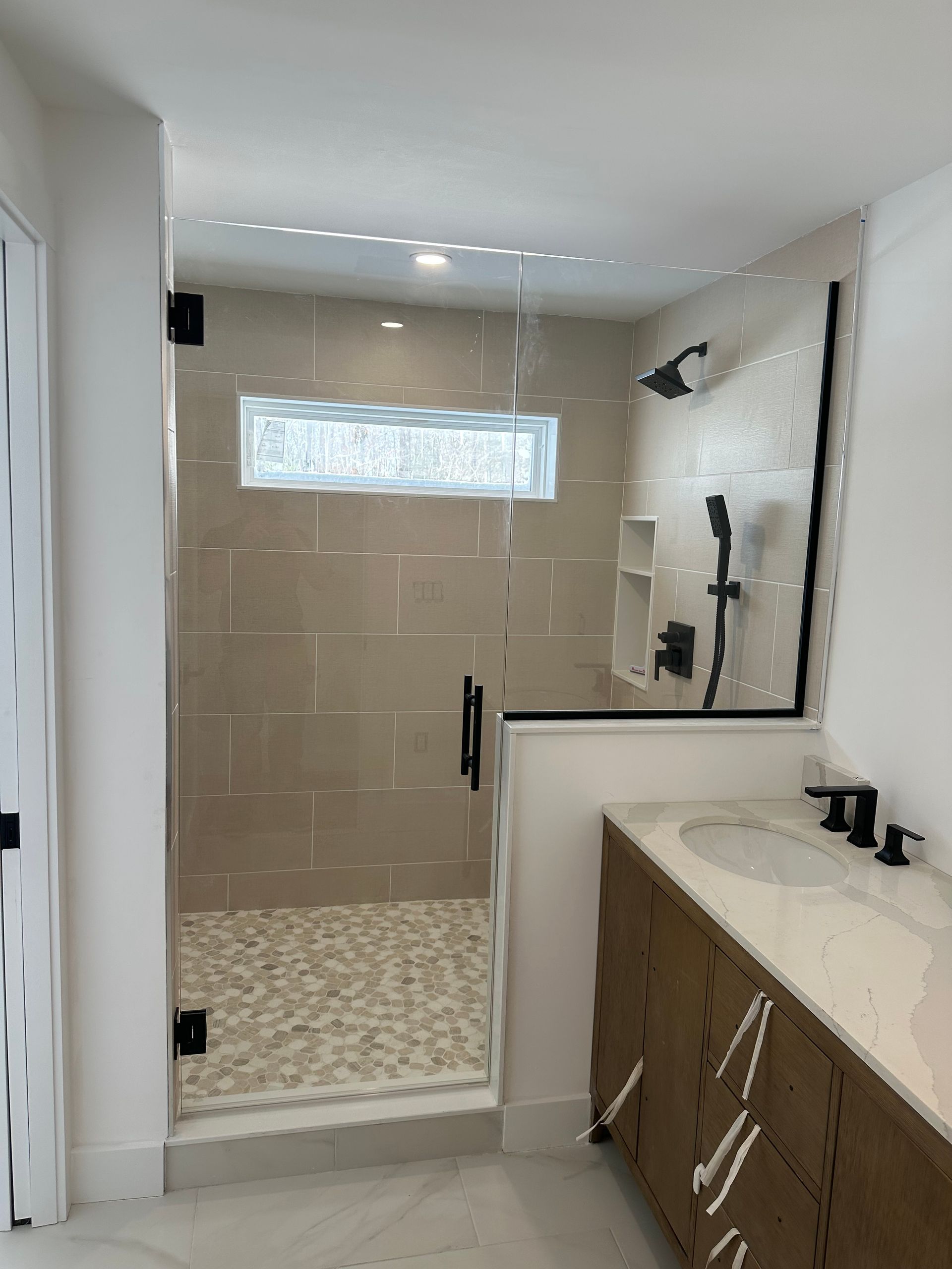 Modern bathroom with glass shower, beige tile, and a vanity on the right