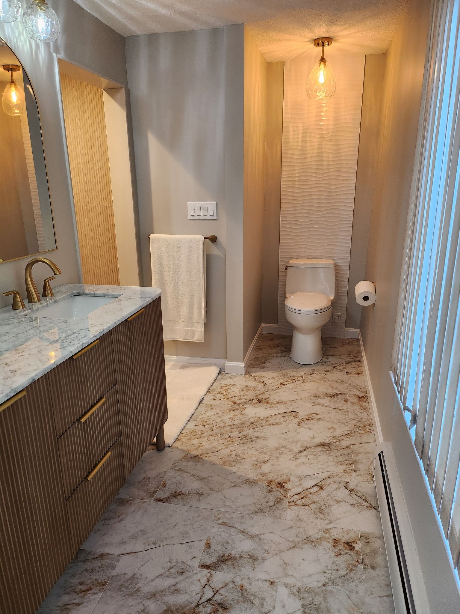 Modern bathroom with marble vanity, toilet, tiled walls, and walk-in shower.