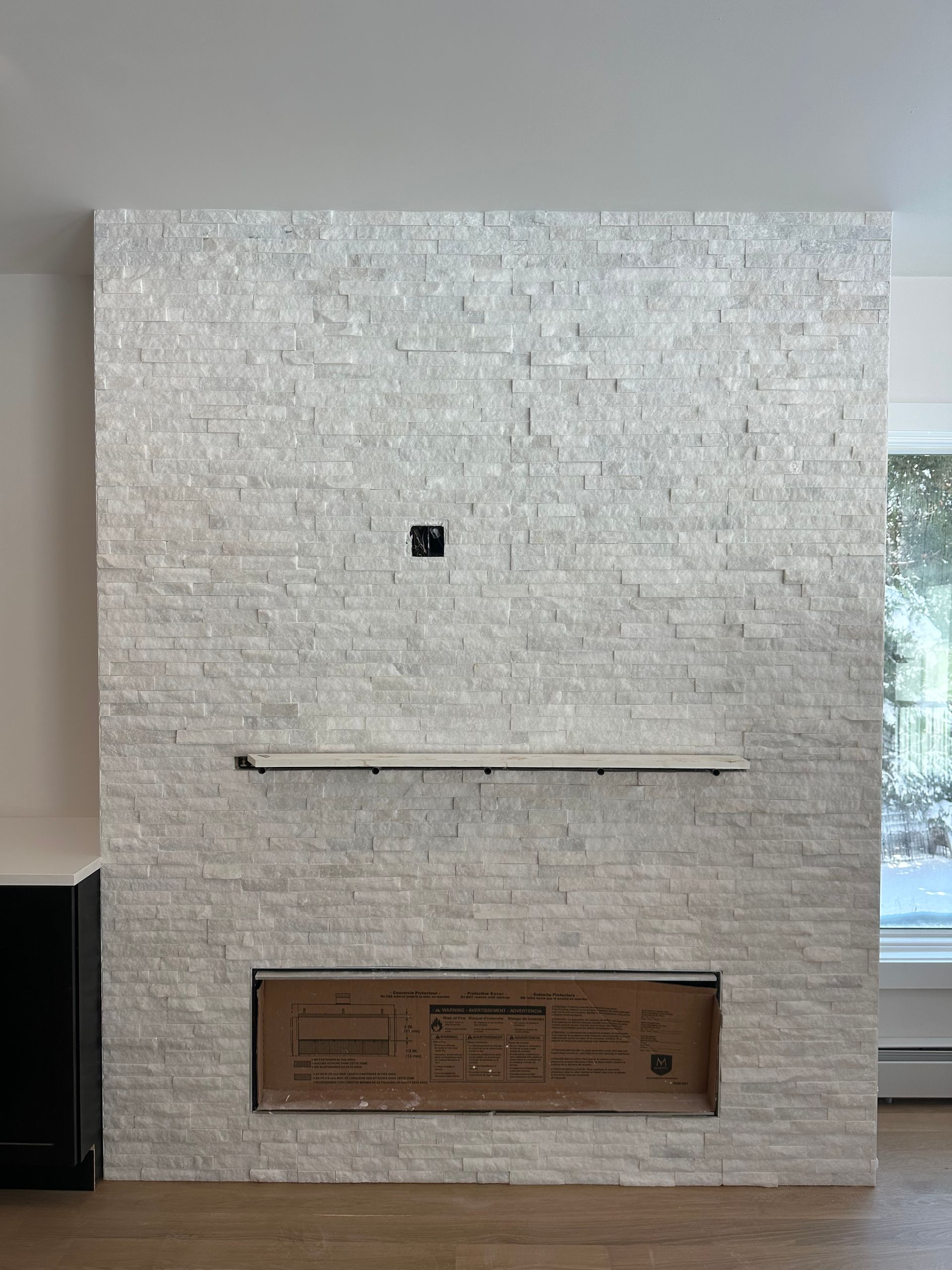 Modern white tiled wall with a narrow shelf and a small framed plaque near the bottom.