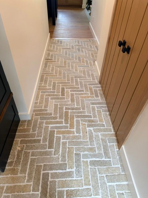 Narrow hallway with a light herringbone runner rug and wooden closet doors along the right wall.
