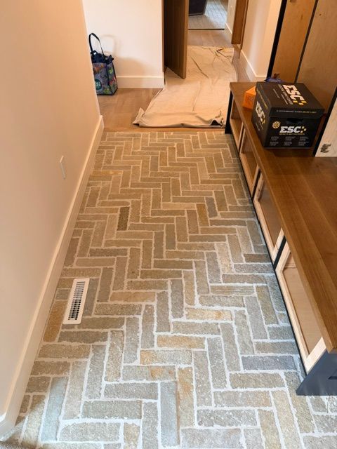 Narrow hallway with a herringbone rug runner, beige walls, and a step-up doorway at the end.