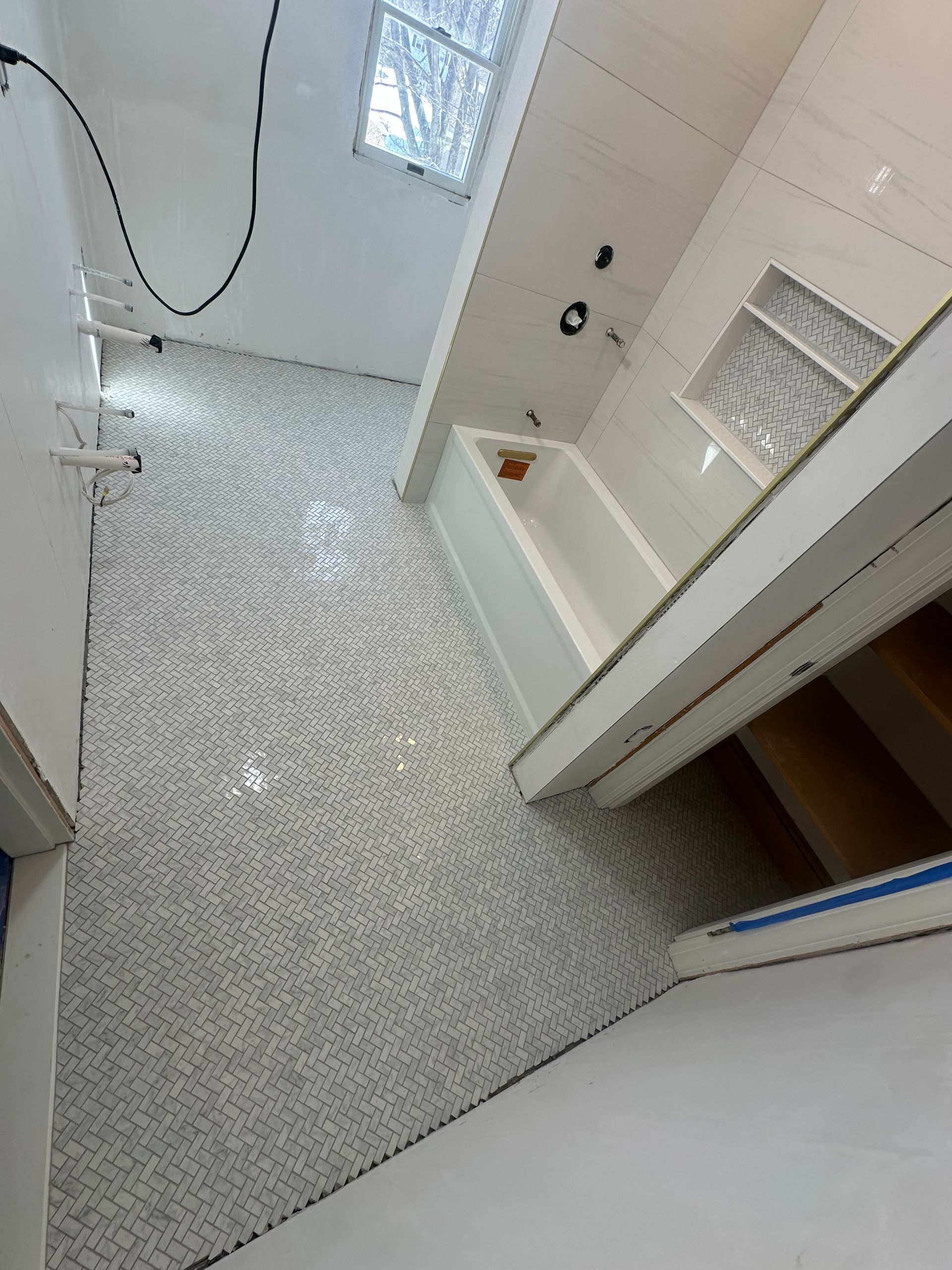 Small tiled bathroom with a shower, white walls, and a partially open door.
