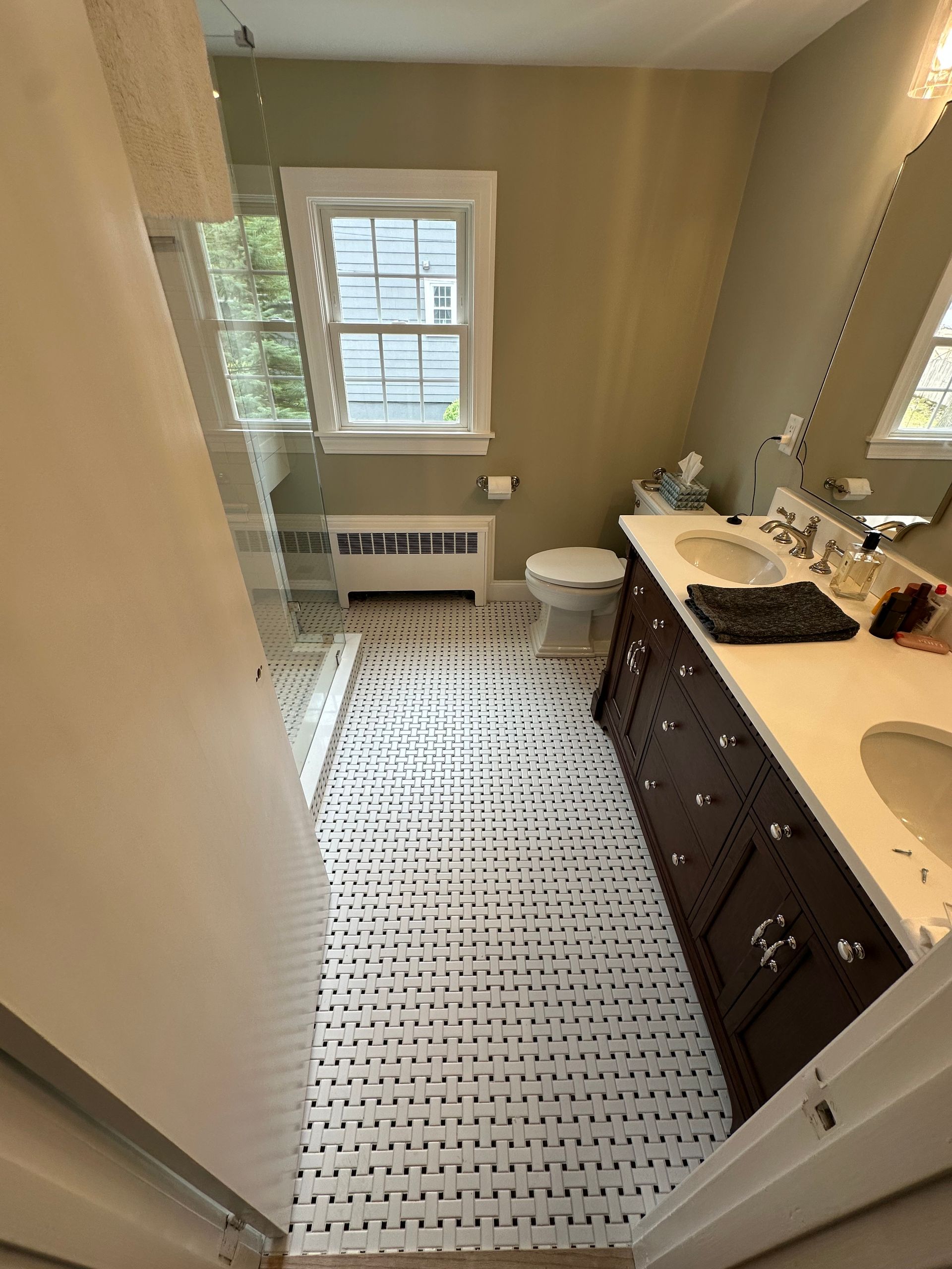 Small bathroom with a window, dark vanity, white sink, toilet, and black-and-white patterned floor.