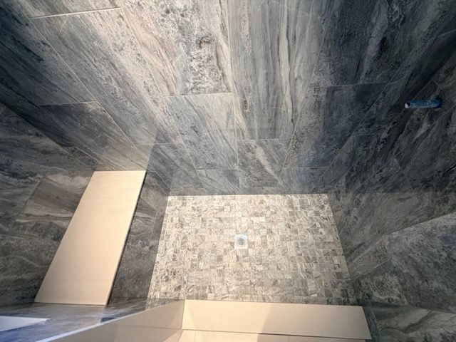 Empty modern shower with gray stone tiles and a bench seat