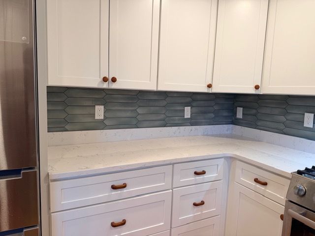 Modern white kitchen with white cabinets, gray tile backsplash, and stainless steel appliances