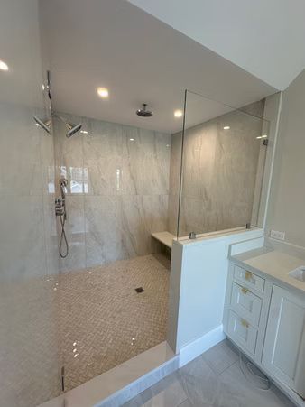 Modern bathroom with a glass-enclosed shower, marble tile, and vanity sink